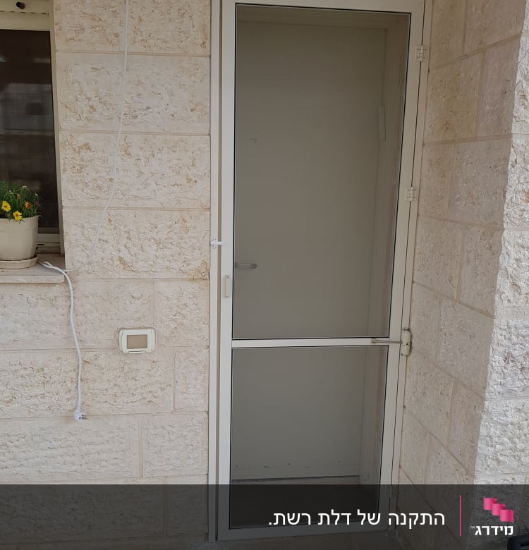 דלת אלומיניום עם רשת על קיר אבן